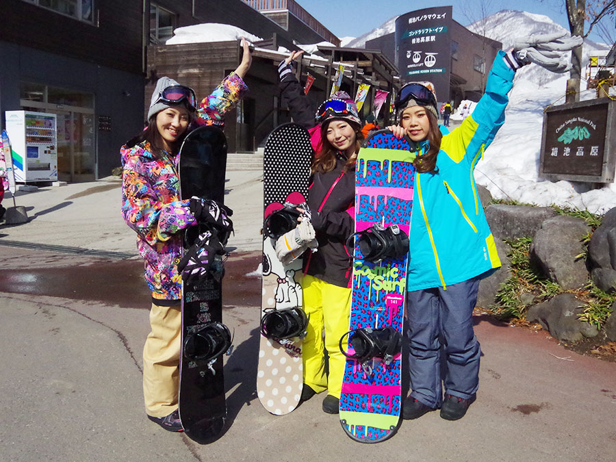 外でスノーボードの板を持った3人の女性