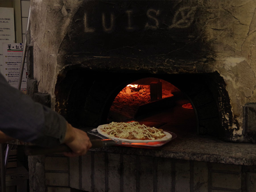 窯に入れられるピザ